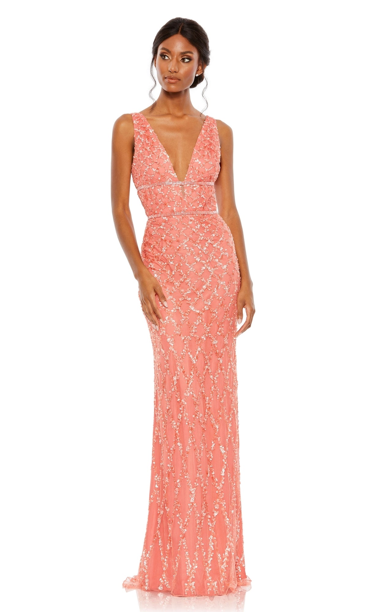 A woman in the Mac Duggal 5669 backless long beaded formal dress, featuring a sleeveless design, floor-length coral fabric, deep V-neckline, and sequin details, stands against a white background.